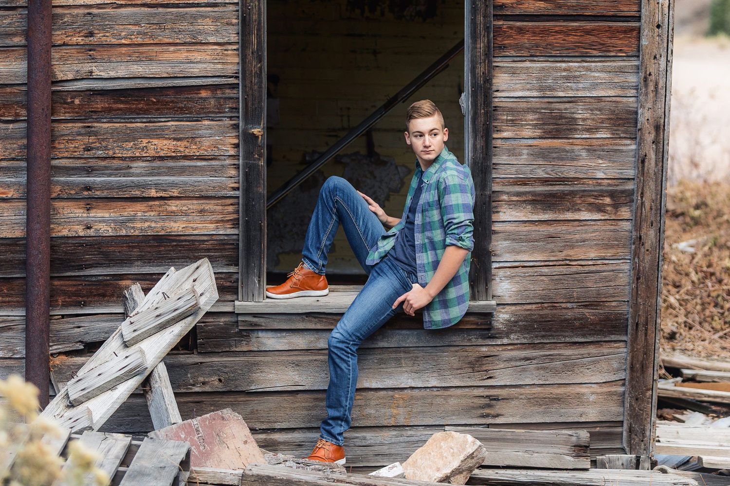 Casual portrait of person in denim sitting on wooden porch steps of rustic building.