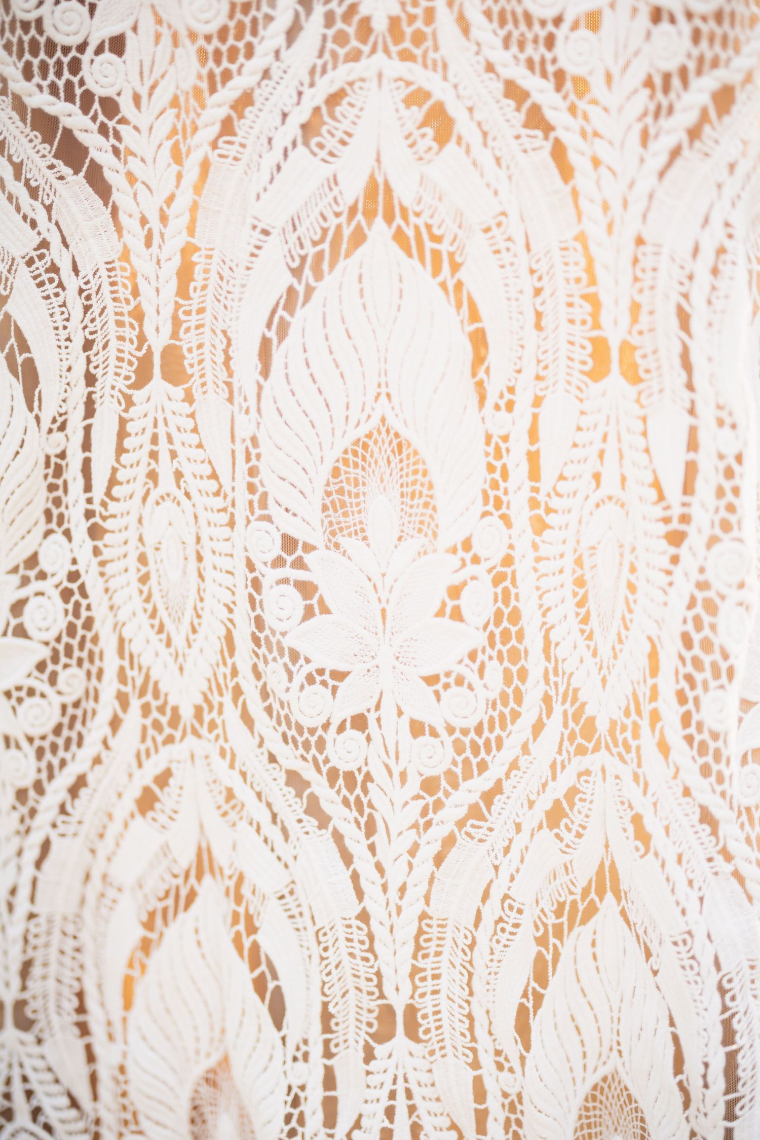 Elegant white lace pattern against warm copper background with floral and geometric design elements.