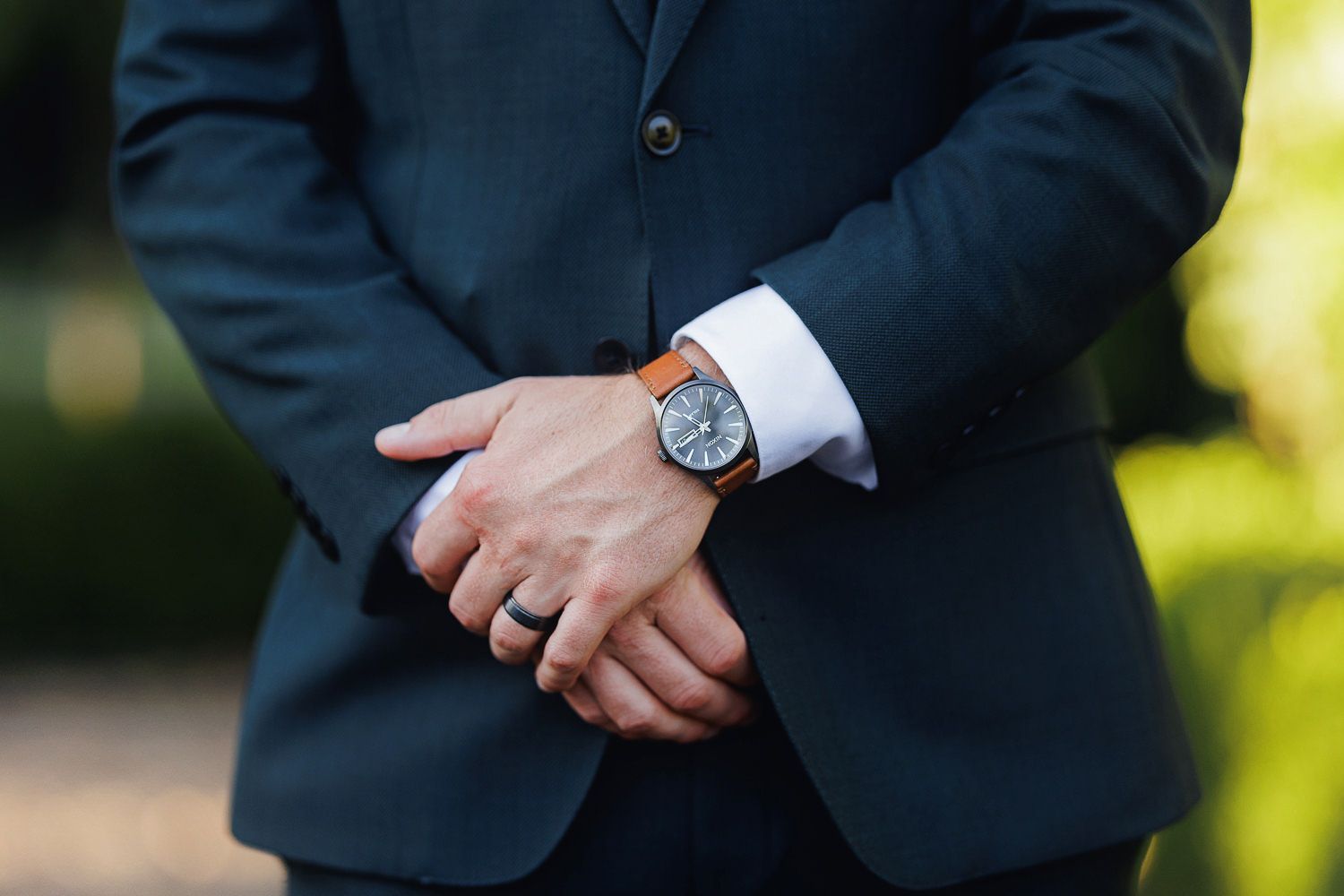 Close-up shots of hands adjusting suit cuffs and wristwatch details in natural outdoor lighting.