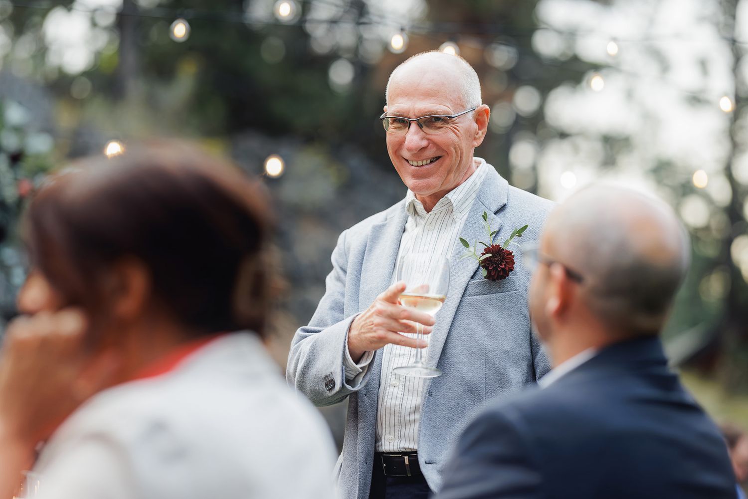 A group of people gathered outdoors for a social event, with drinks and laughter in a casual setting.