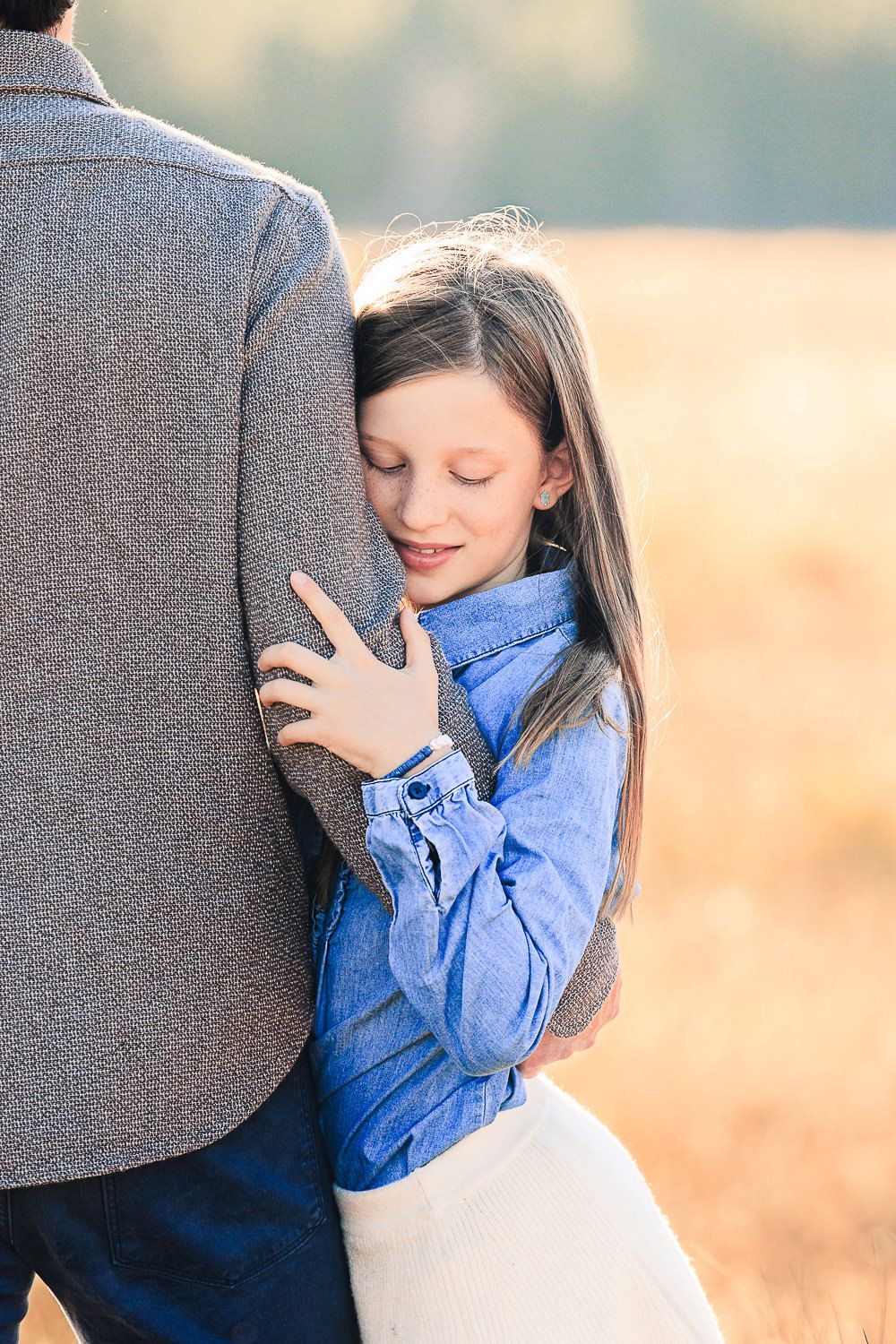 An intimate moment captured showing a tender embrace outdoors in soft natural lighting.