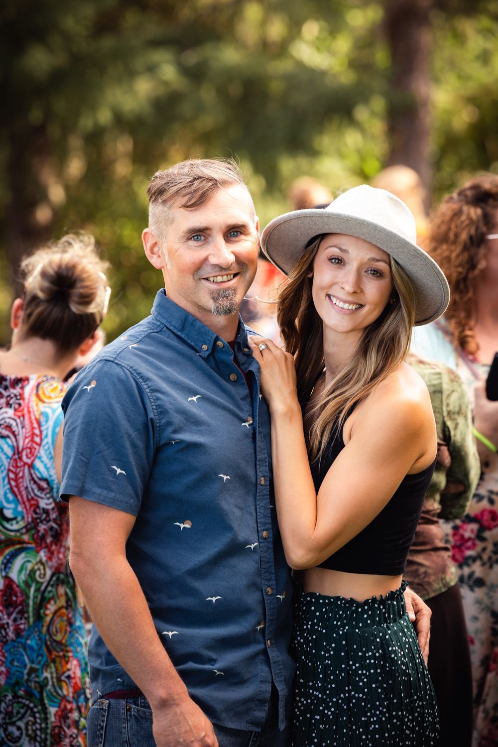 A stylish couple enjoying themselves at an outdoor celebration among other party guests.
