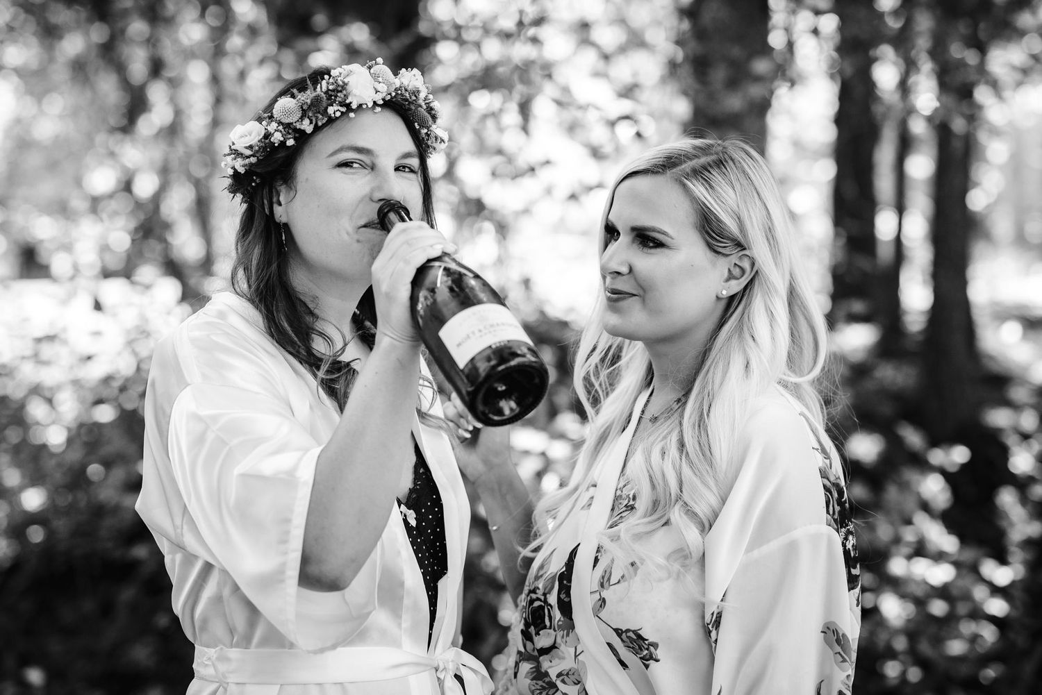 Two people in white robes sharing a drink outdoors in a black and white candid photo.