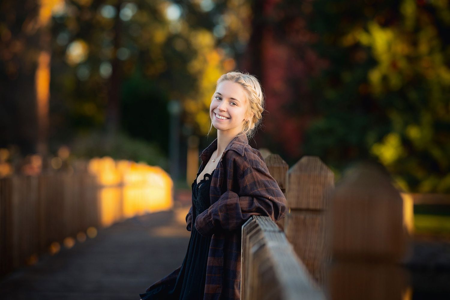 A soft evening portrait against a wooden fence with warm sunset lighting.