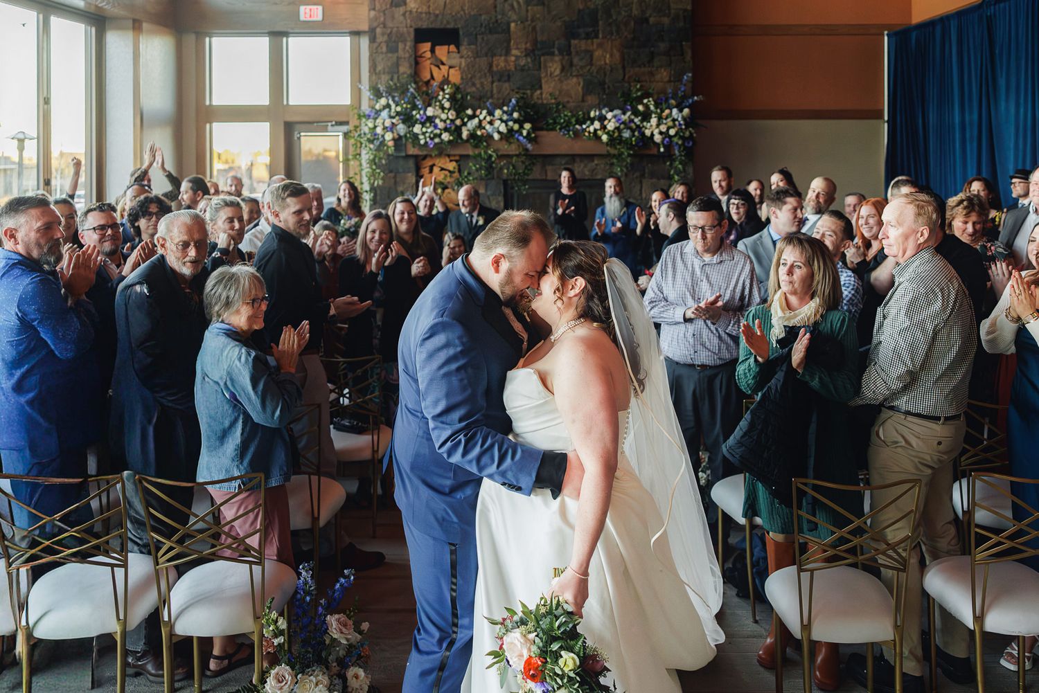 A wedding ceremony sequence showing a couple sharing their first kiss as guests look on with joy at an indoor venue.
