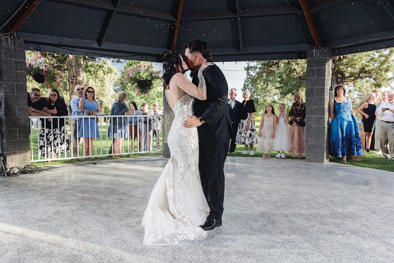 A romantic first dance takes place under a gazebo as wedding guests look on from the sidelines during a ceremony.