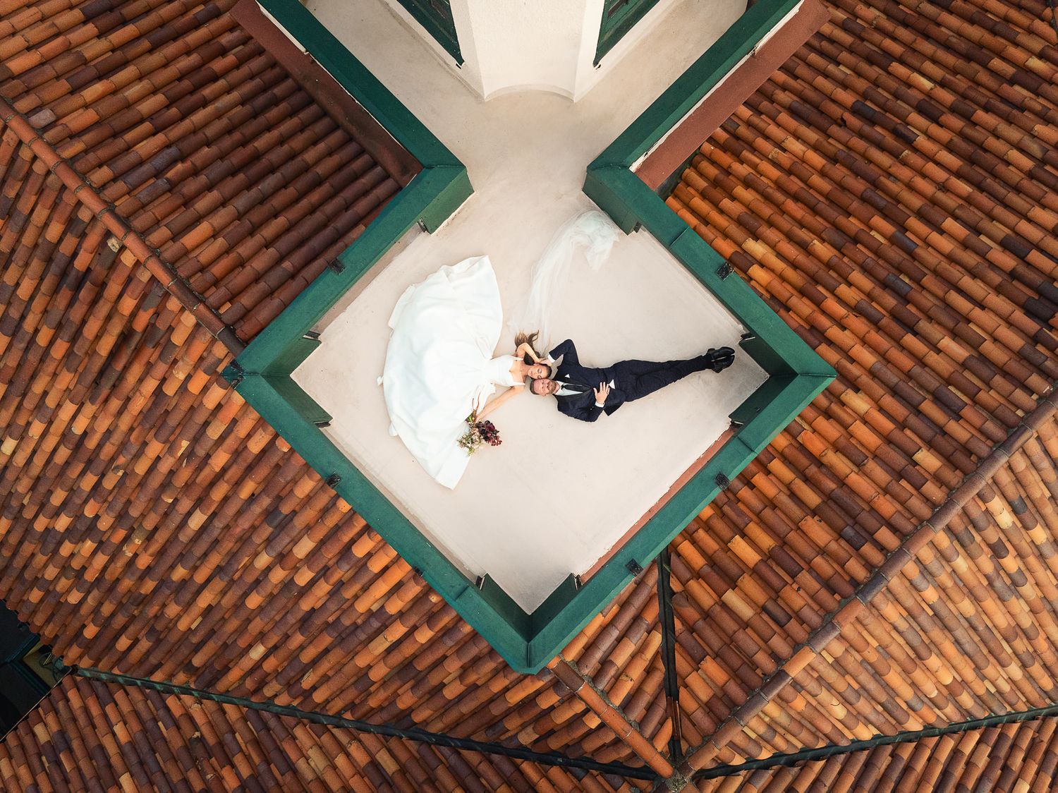 Aerial view of a couple dancing in a white courtyard surrounded by terracotta roof tiles.