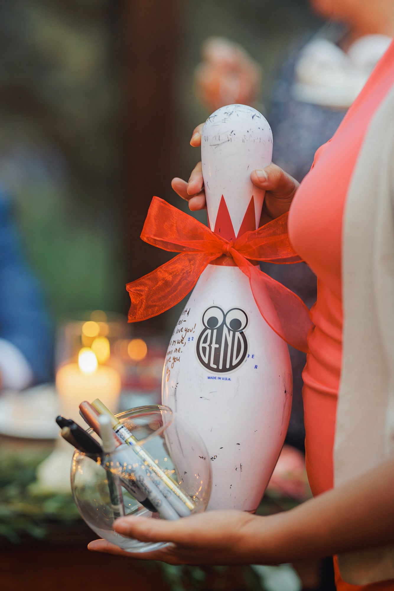 A sequence of images showing a white bowling pin being decorated with googly eyes and a red cape for a creative craft project.