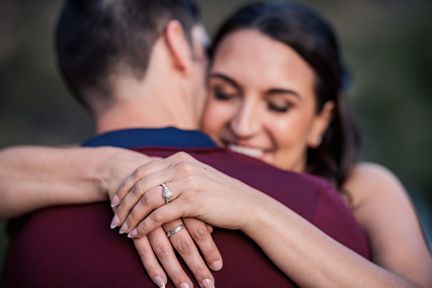 Ring sparkles on hand during romantic outdoor engagement moment.
