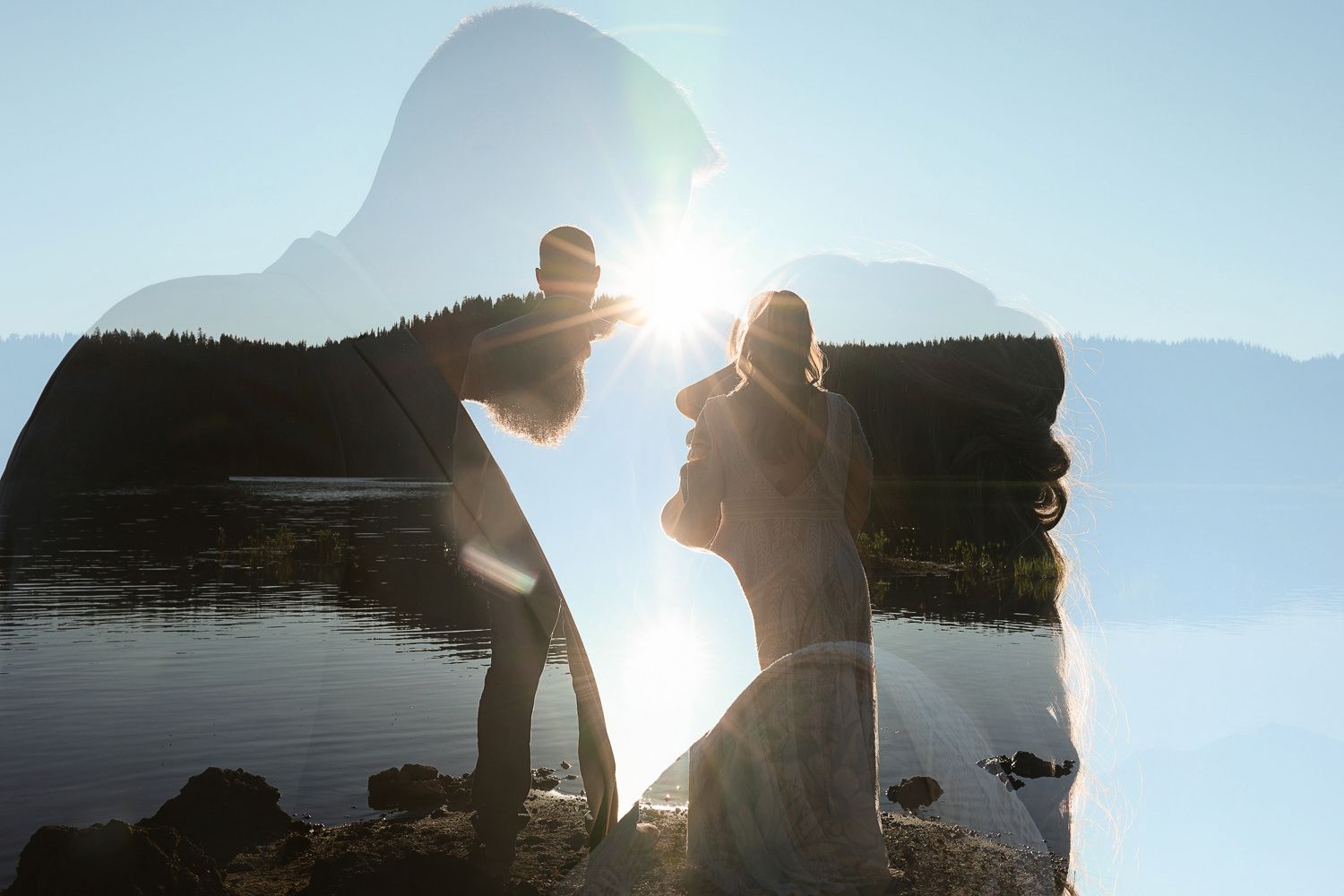 A silhouetted figure stands at the edge of a misty lake with mountains in the background during sunset.