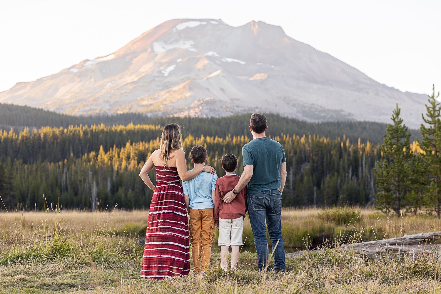 A group of people stand together admiring the majestic mountain landscape at dusk in a tranquil wilderness setting.