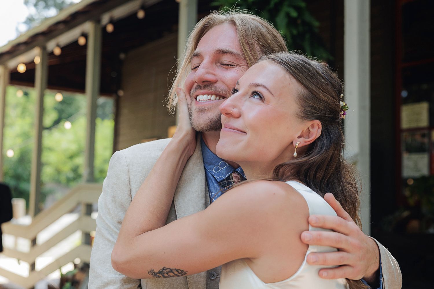 A joyful, intimate outdoor moment between two people embracing and laughing together in natural lighting.