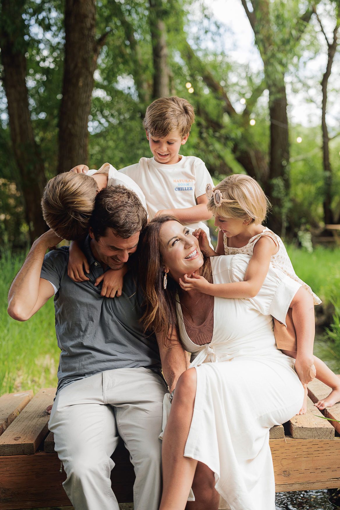 Family sharing a playful moment together on wooden bench in park setting.