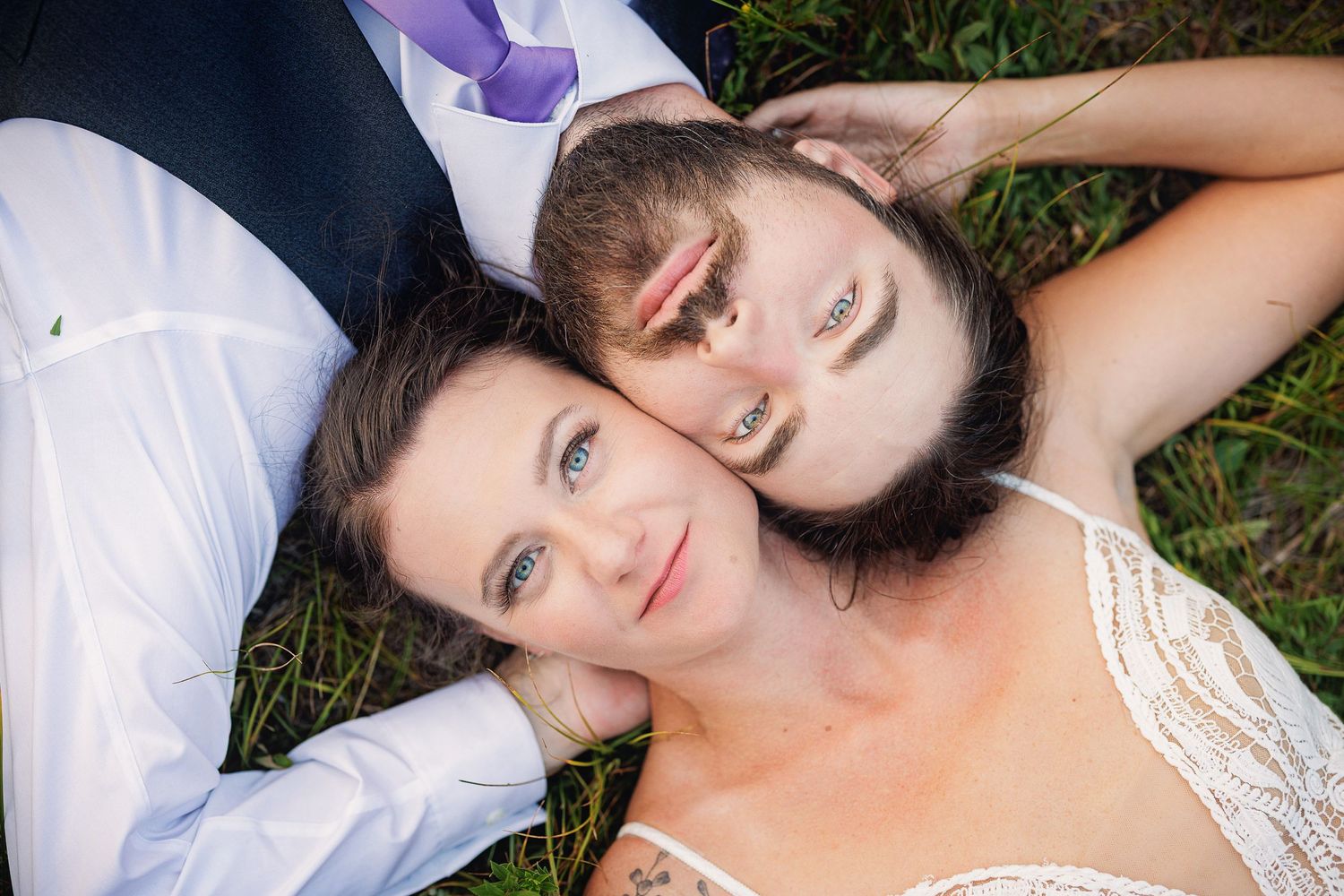 A couple lying on grass viewed from above creating a symmetrical composition.