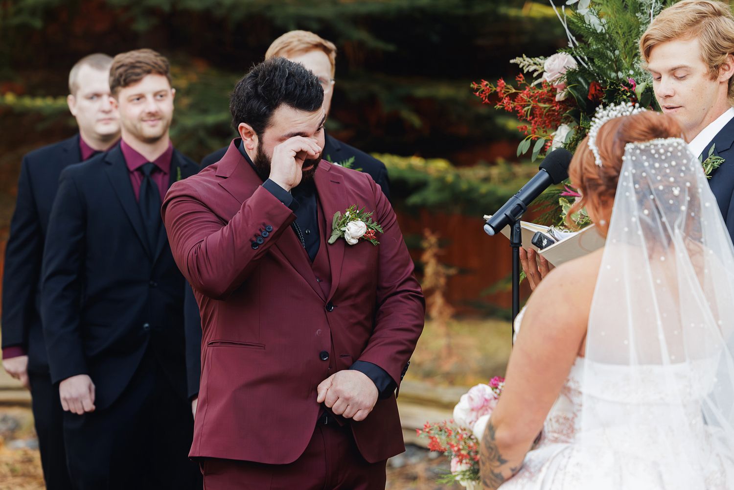 Emotional reactions during an outdoor autumn wedding ceremony with burgundy and navy attire.
