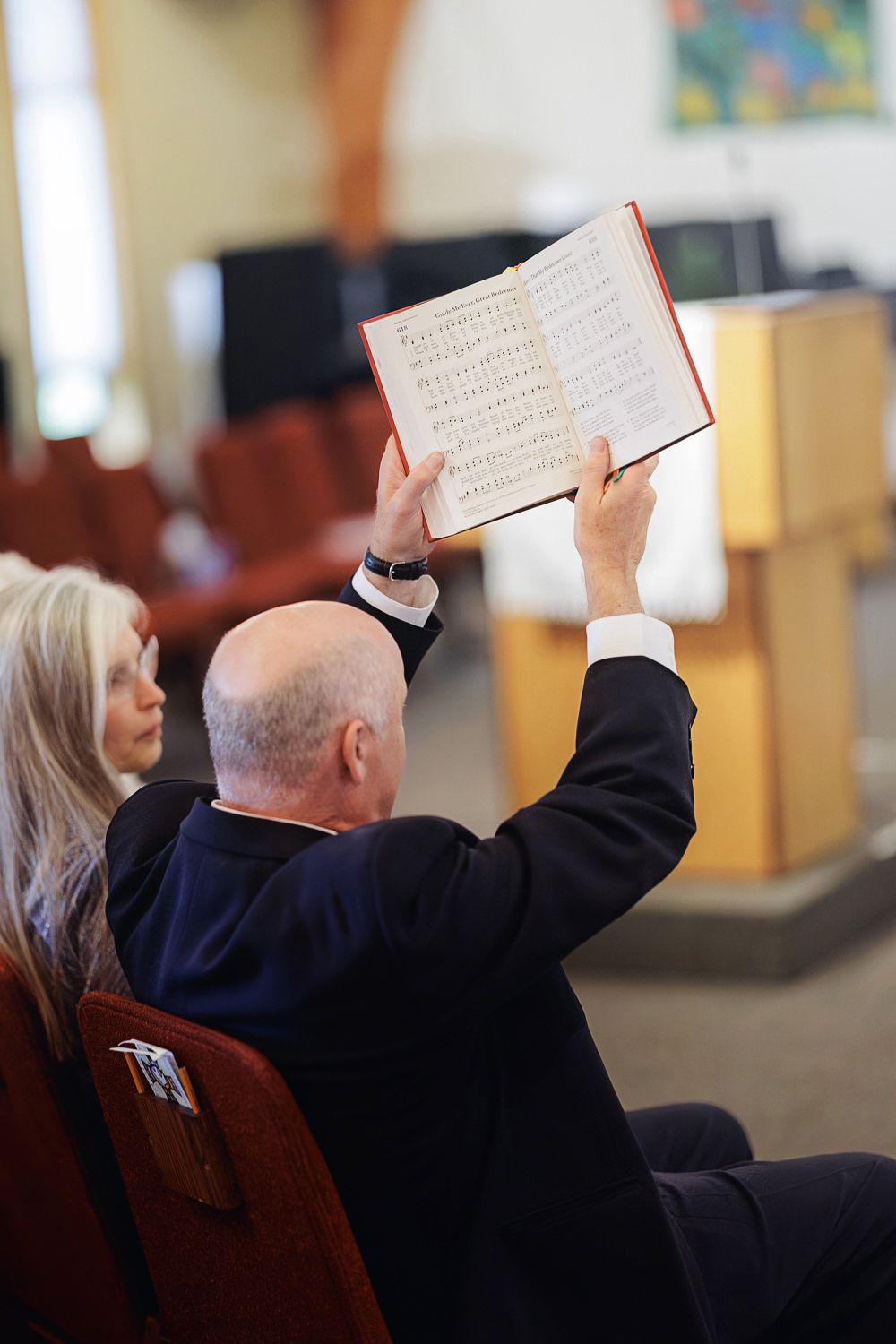 People hold up prayer books during a church service as they participate in religious worship.