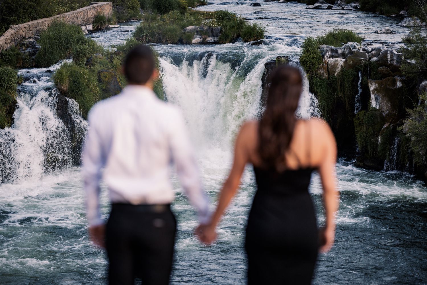 A sequence of photos showing people walking behind a cascading waterfall at a scenic natural attraction.