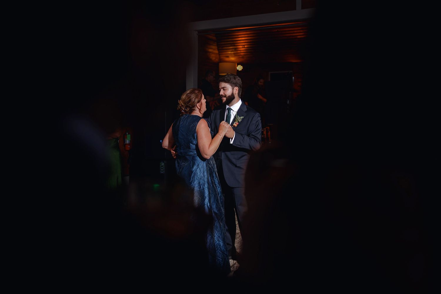 Couple sharing a romantic dance in dim lighting, man in suit and woman in blue dress at a formal event.