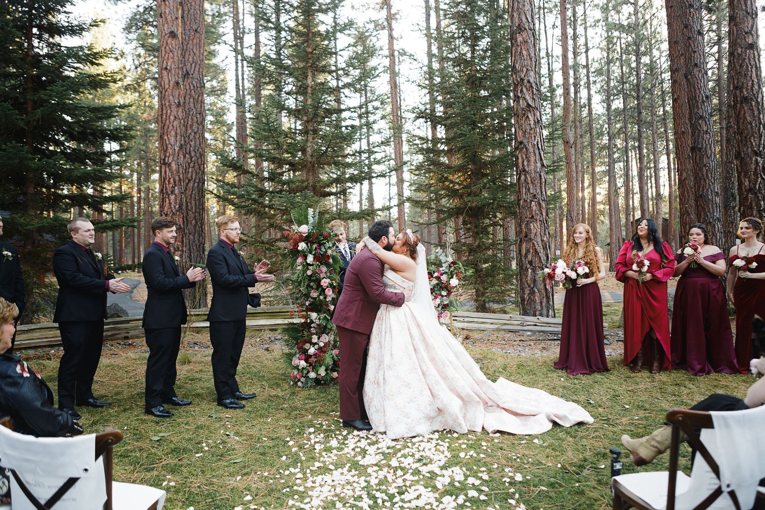 Wedding ceremony setup in a winter forest with chairs arranged in rows and a decorated floral arch.