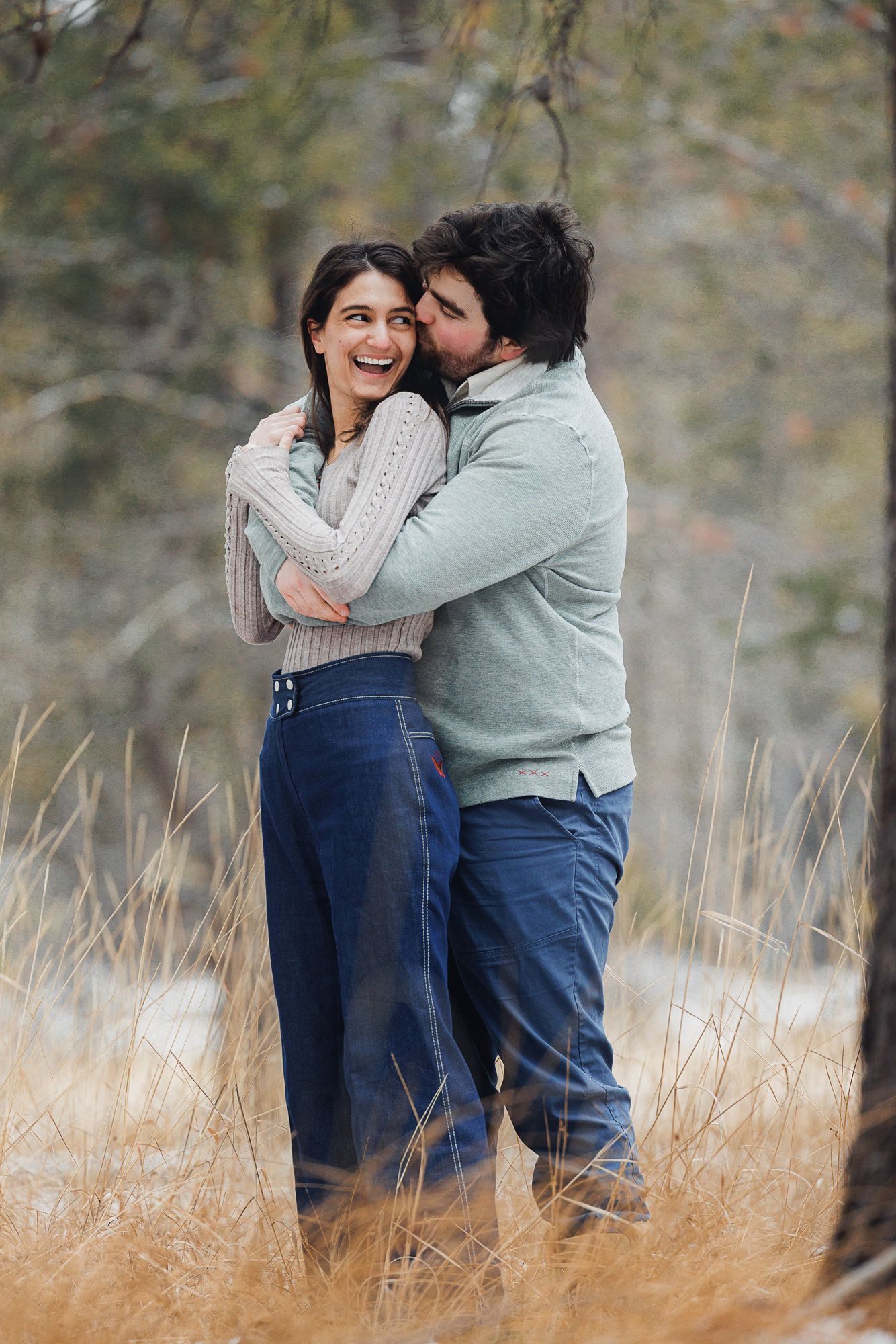 A couple shares intimate moments while standing in tall golden grass during an autumn outdoor photoshoot.