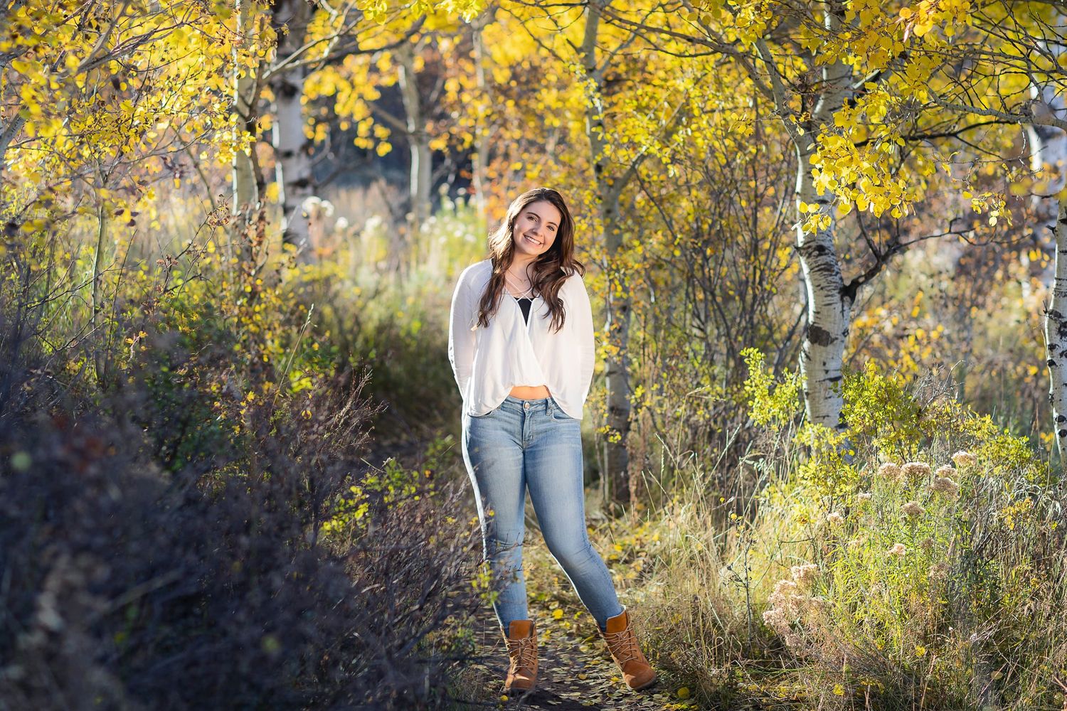 An autumn portrait session among yellow aspen trees in a natural setting.