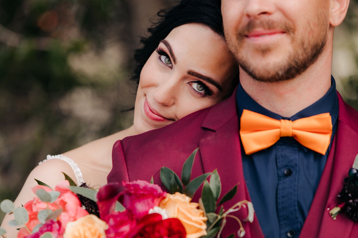 A close-up shot featuring vibrant pink and red wedding flowers with an orange bowtie accent.