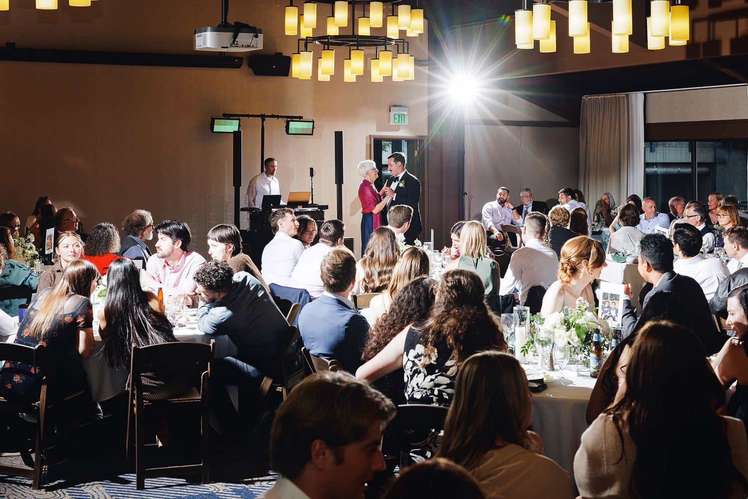 Guests seated at round tables during an elegant banquet event in a dimly lit ballroom with warm lighting.