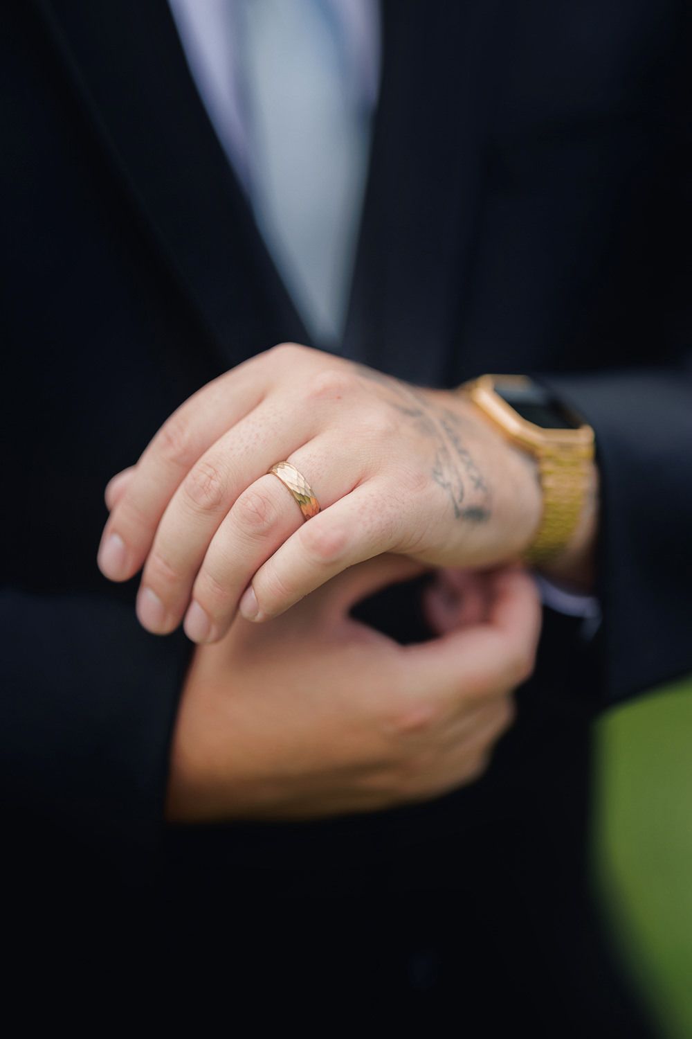 Close up detail shot of hands wearing elegant gold jewelry against a dark background.