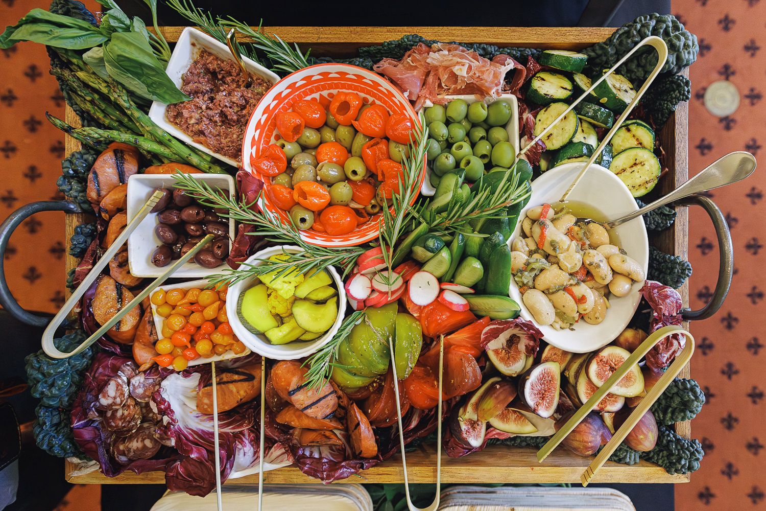 Overhead shot of a colorful spread of Mediterranean appetizers and dips with vegetables, olives, and bread on a wooden board.