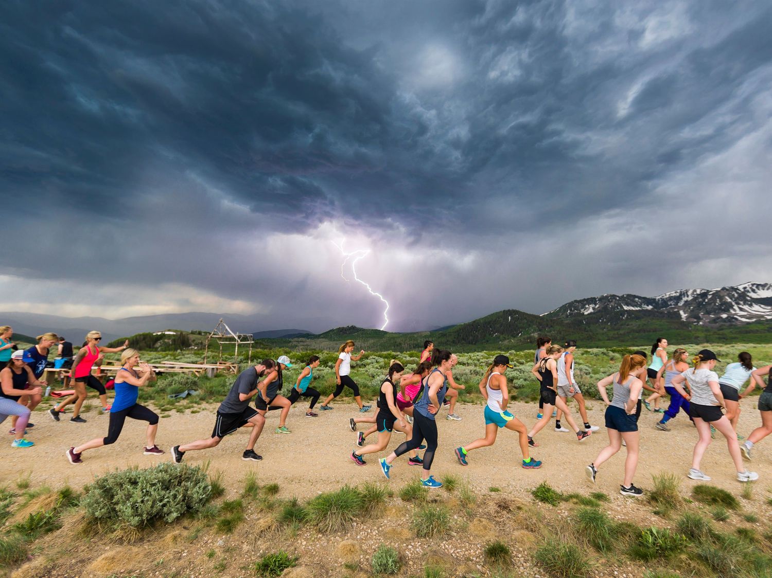 Group running across desert landscape with dramatic storm clouds and lightning in background.