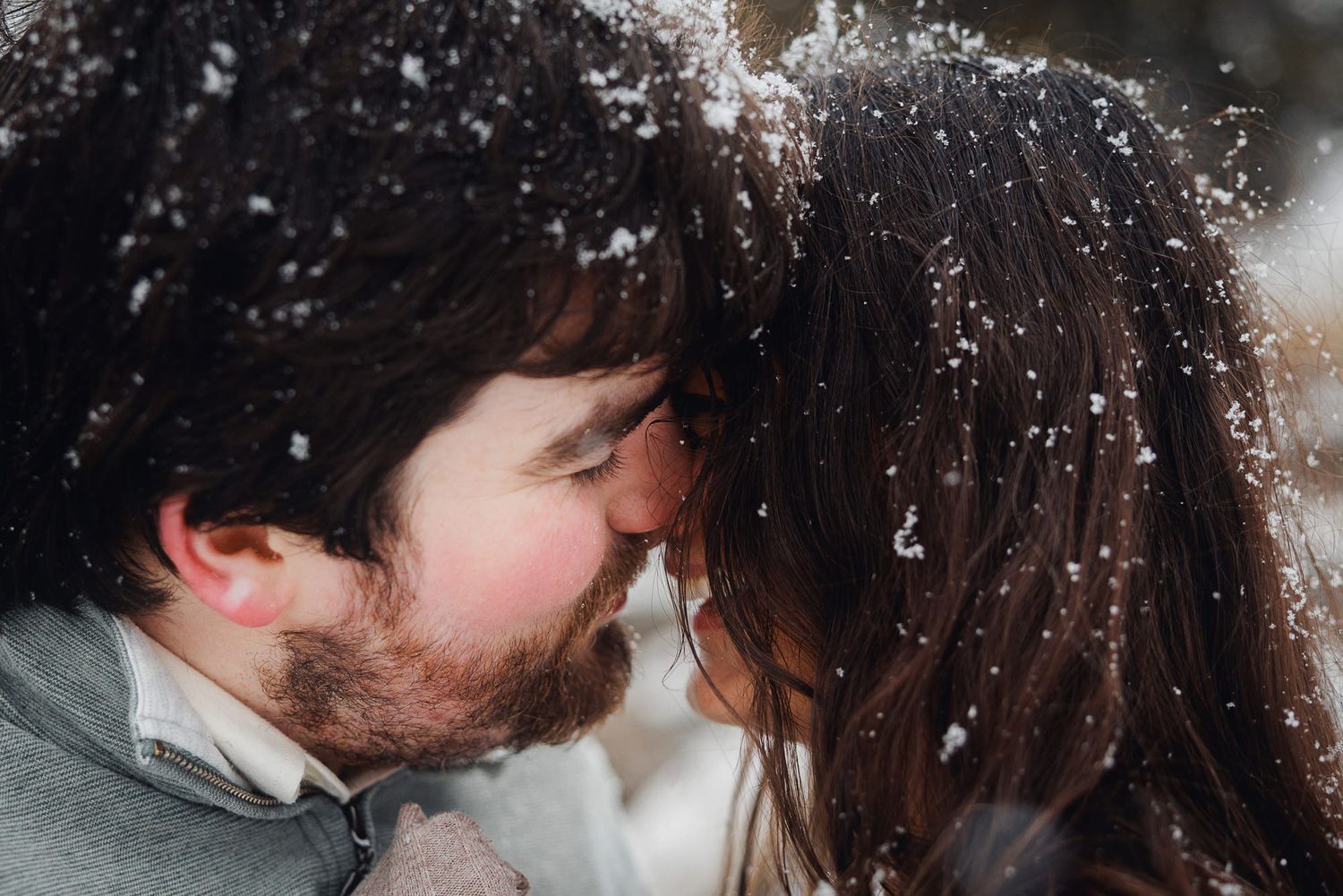 A romantic couple sharing an intimate kiss outdoors in a close-up shot with dark moody lighting.