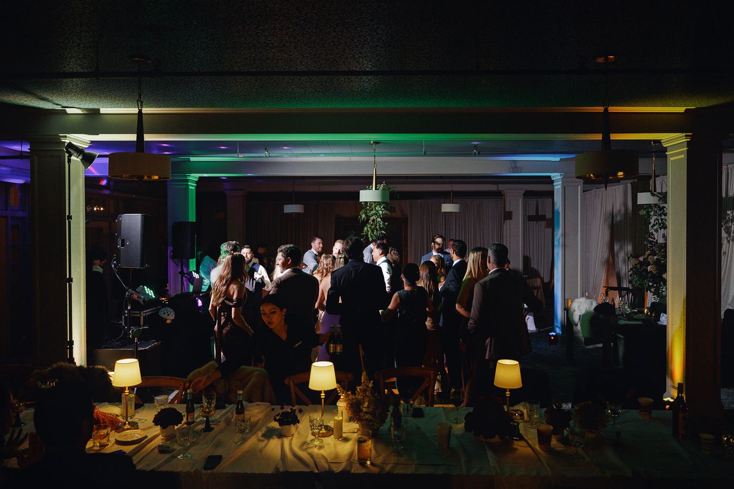 Guests mingle under colorful neon lights at an elegant evening event in a dimly lit venue.