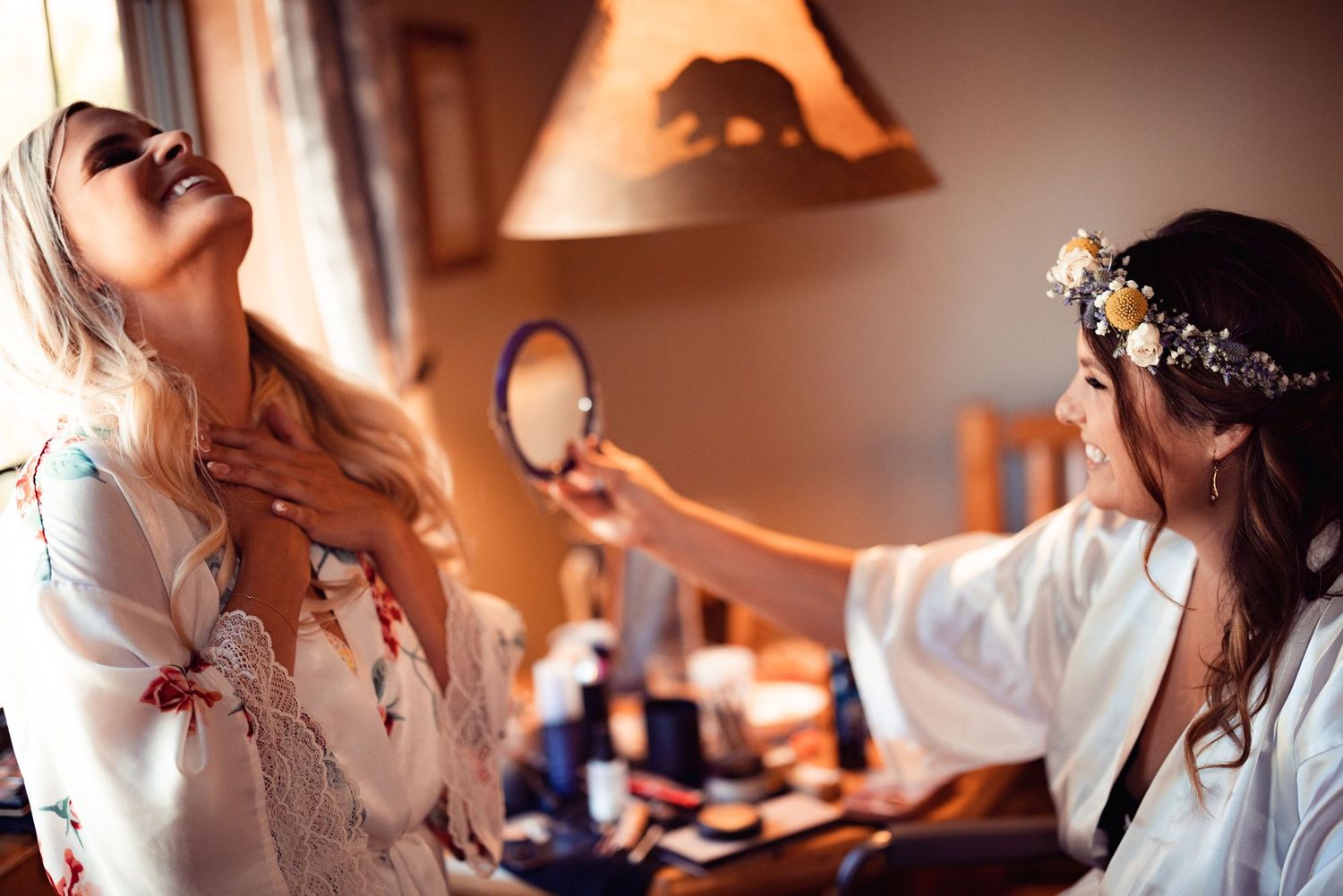 A makeup artist applies cosmetics while a client sits in the salon chair with their head tilted back.