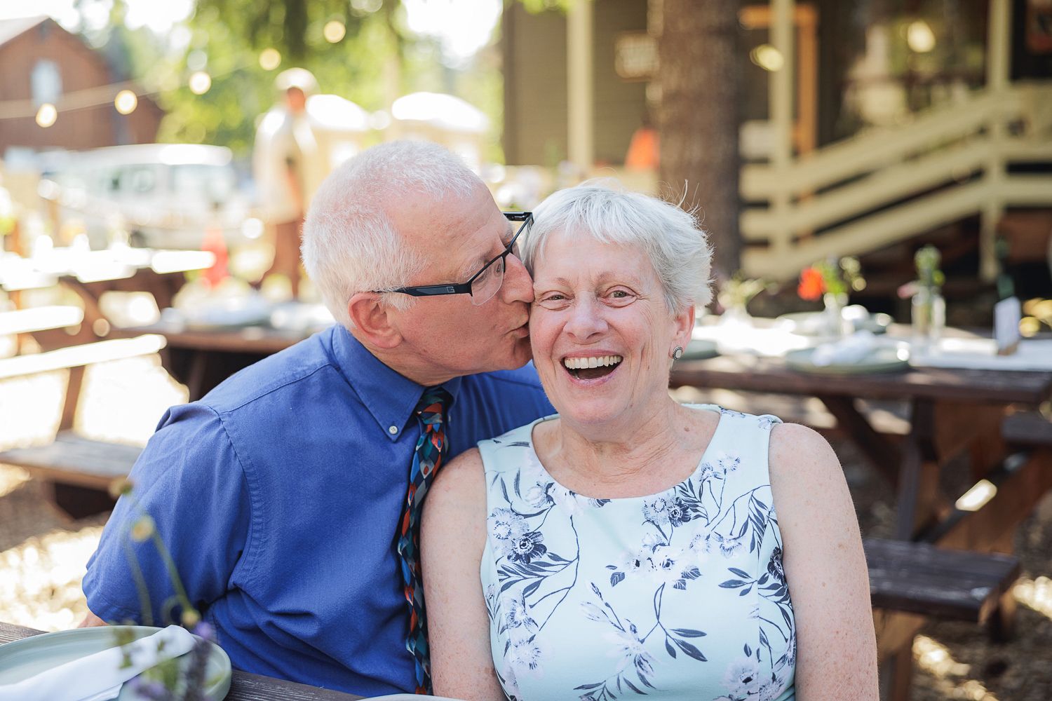 Sweet elderly couple sharing a tender moment on an outdoor patio during a sunny afternoon.