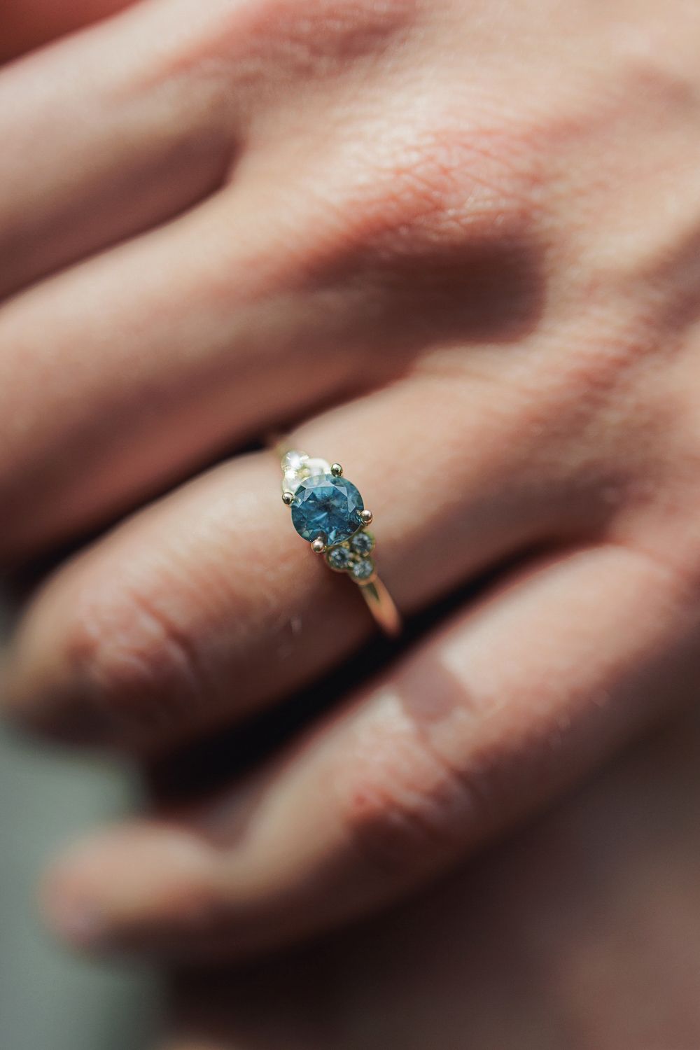 Macro photography series showing a turquoise diamond ring in varying levels of focus and blur on a hand.