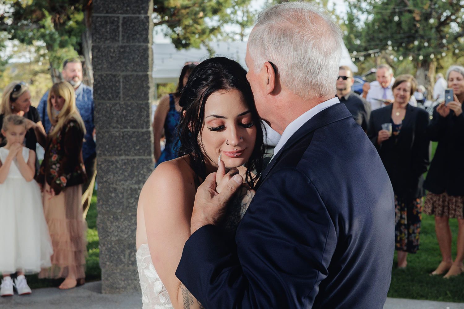 Wedding couple shares first dance surrounded by guests at outdoor reception celebration.