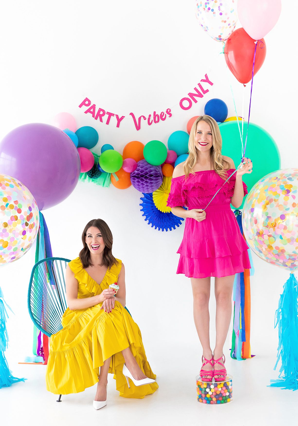 Colorful party setup with balloons, streamers and decorations against white backdrop.