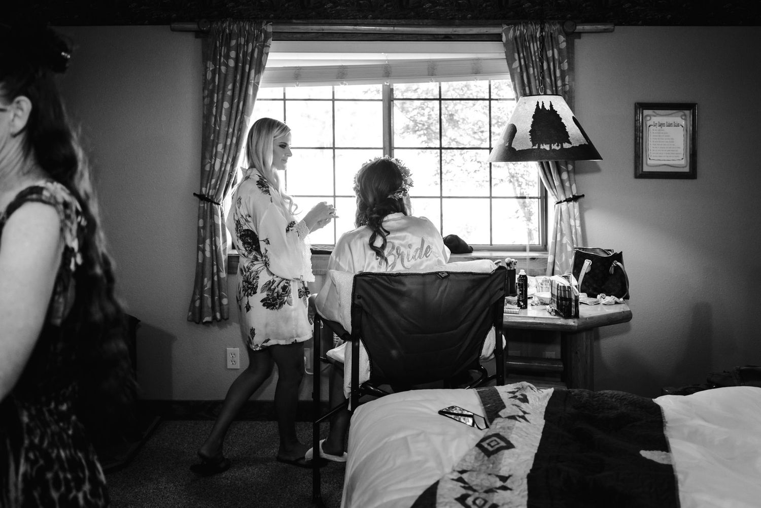 A black and white photo shows people getting ready for a special occasion in a small room with a window and curtains.