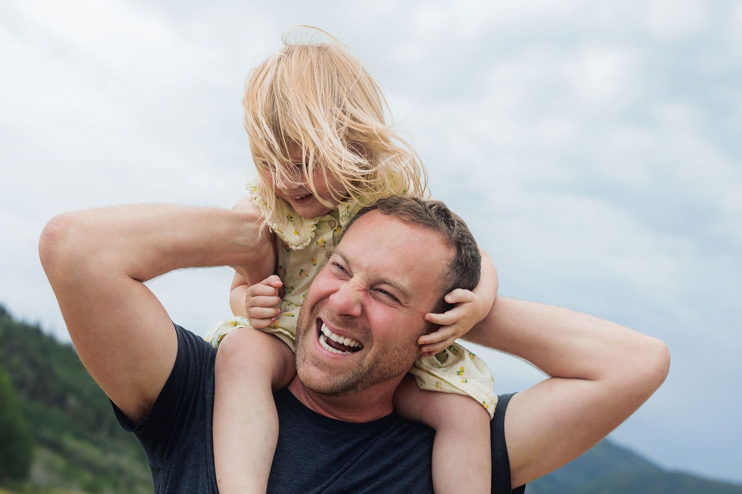 Playful outdoor moment captured against mountain backdrop on a cloudy day.