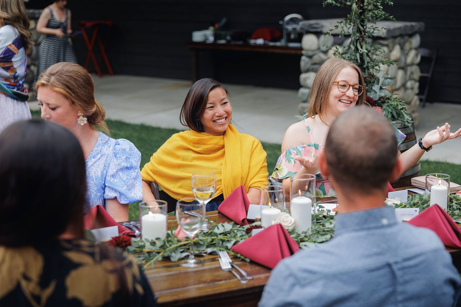 People enjoying drinks and conversation at an outdoor restaurant patio on a sunny day.