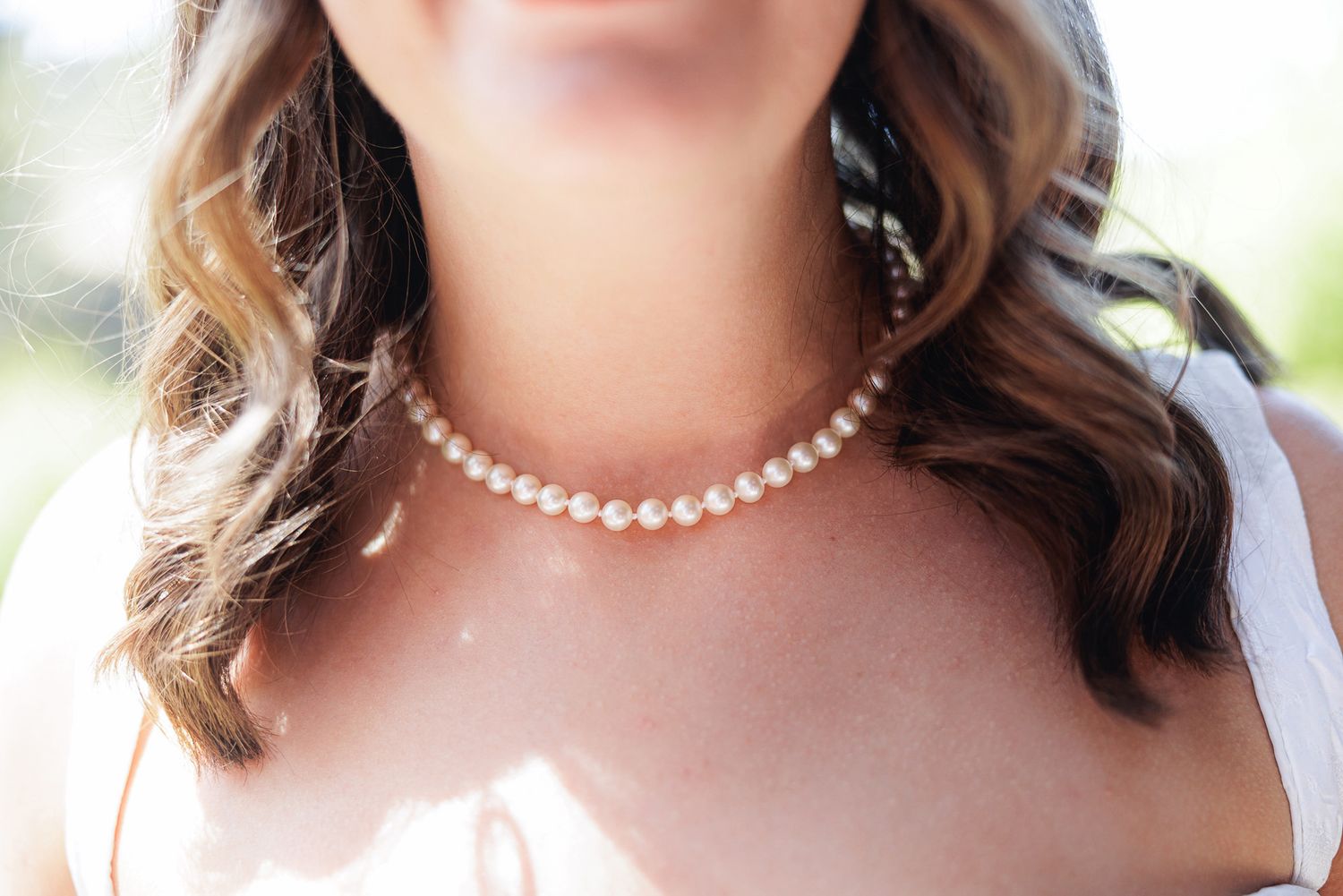 Close-up of a bride wearing a classic pearl choker necklace on her wedding day.