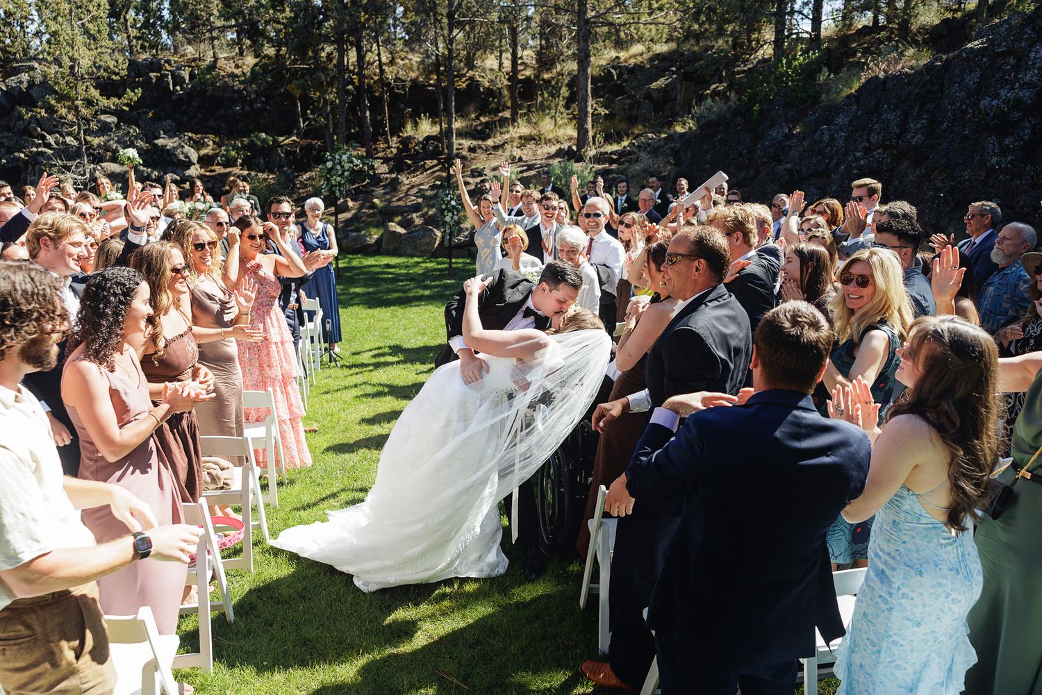 Joyful newlyweds celebrated by cheering guests as they walk back down the aisle after outdoor wedding.