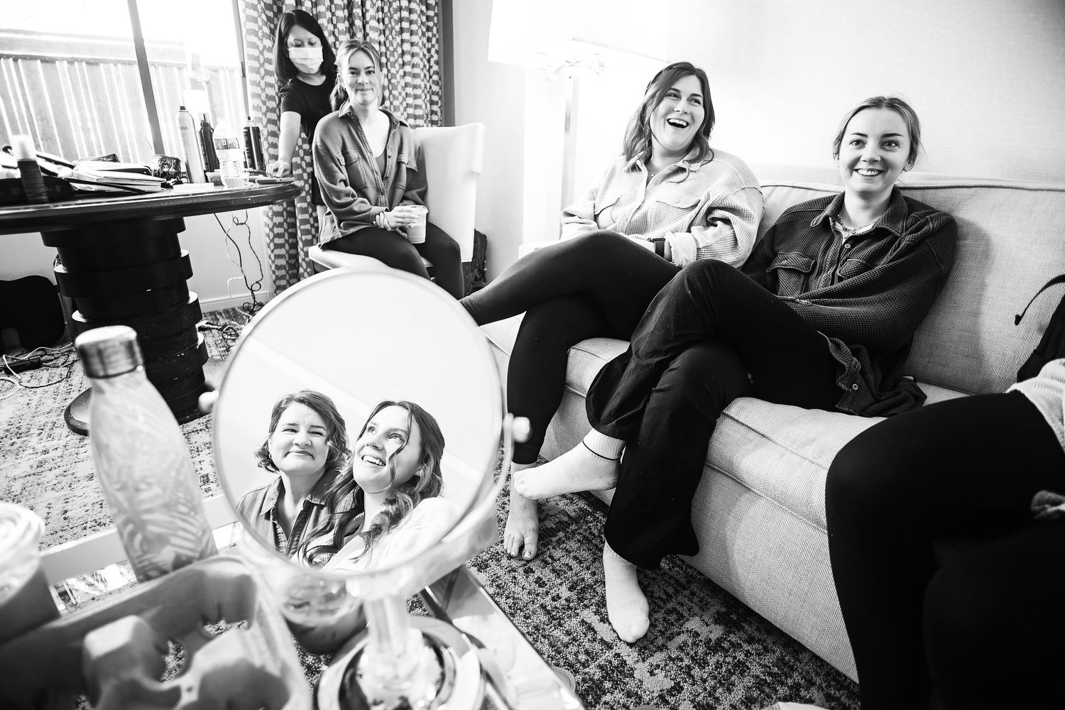 Black and white photo of friends relaxing on a couch with reflection in mirror.