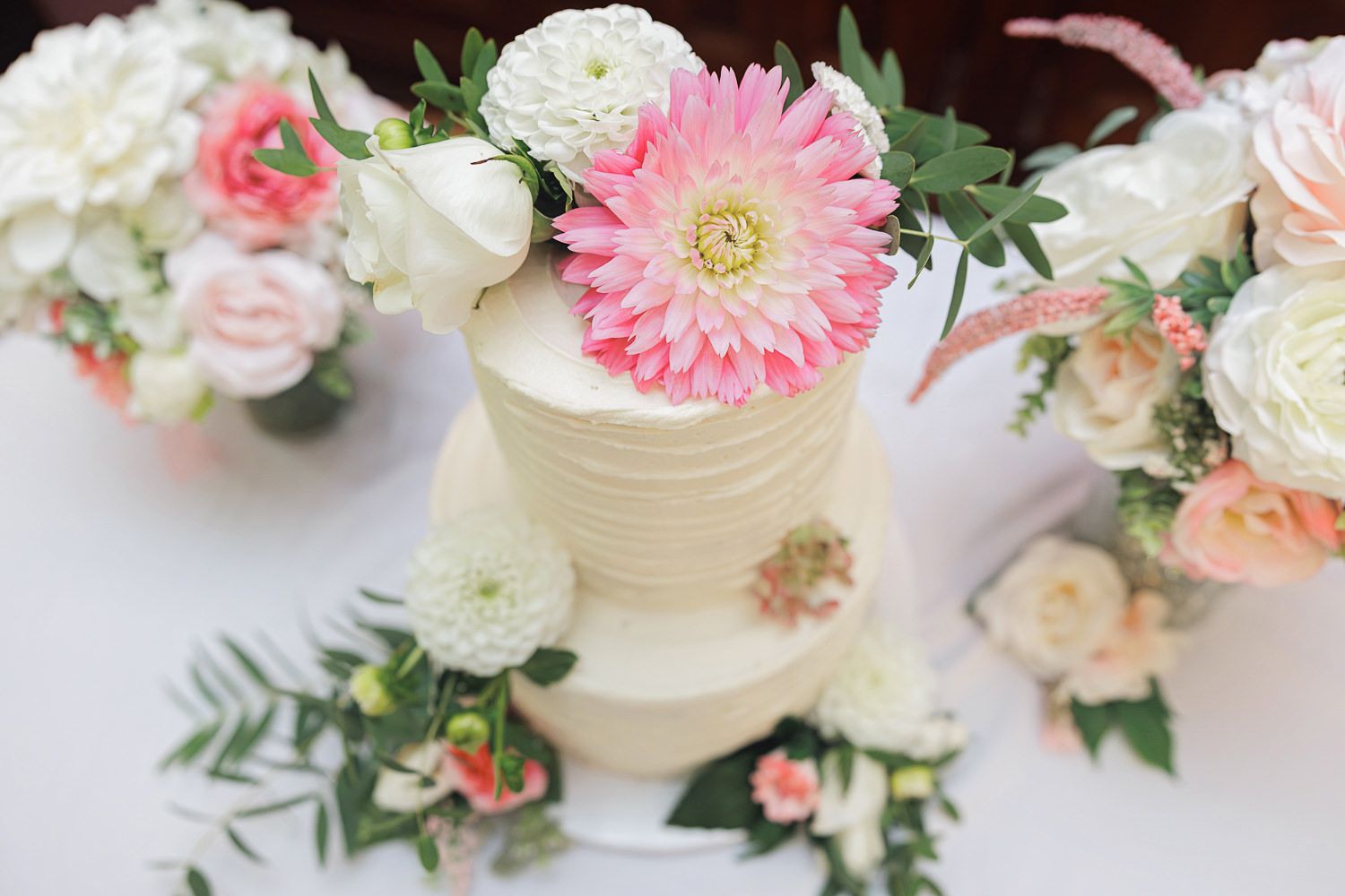 Floral wedding cake decorations featuring delicate pink and white blooms with greenery accents.