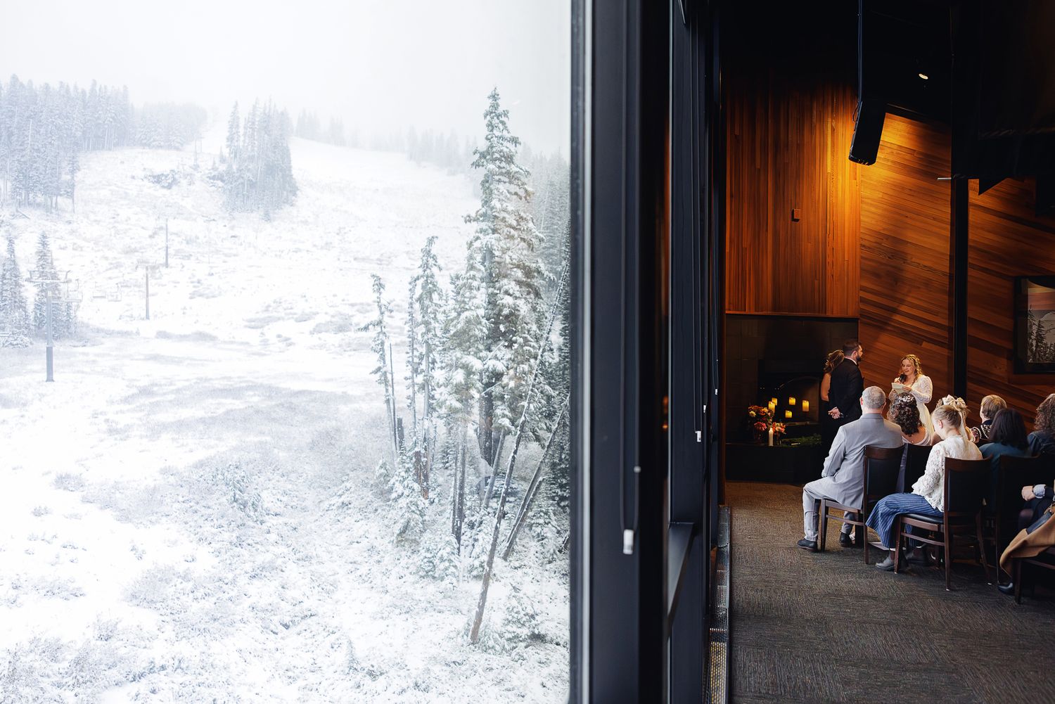 View from a cozy mountain lodge window showing snow-covered slopes and evergreen trees outside while diners enjoy warmth inside.