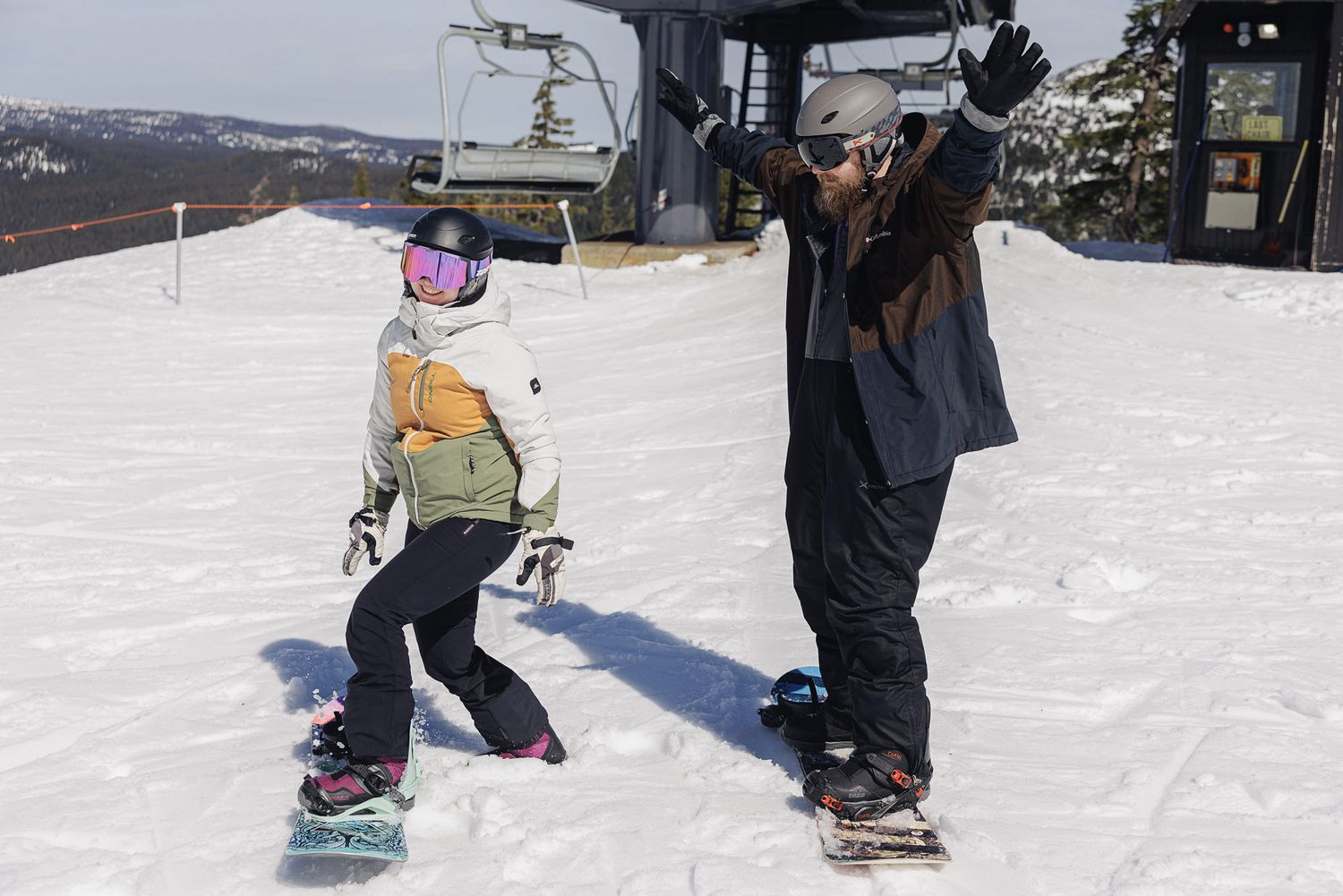 Two people, a man and a woman, are snowboarding on a snowy slope.