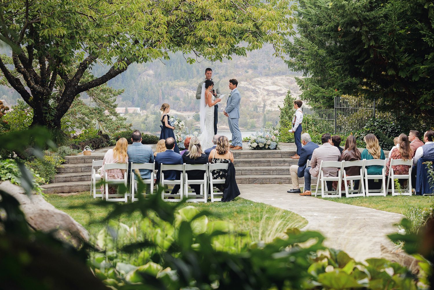 Scenic outdoor wedding venue with rows of white chairs set up against a mountain landscape backdrop.