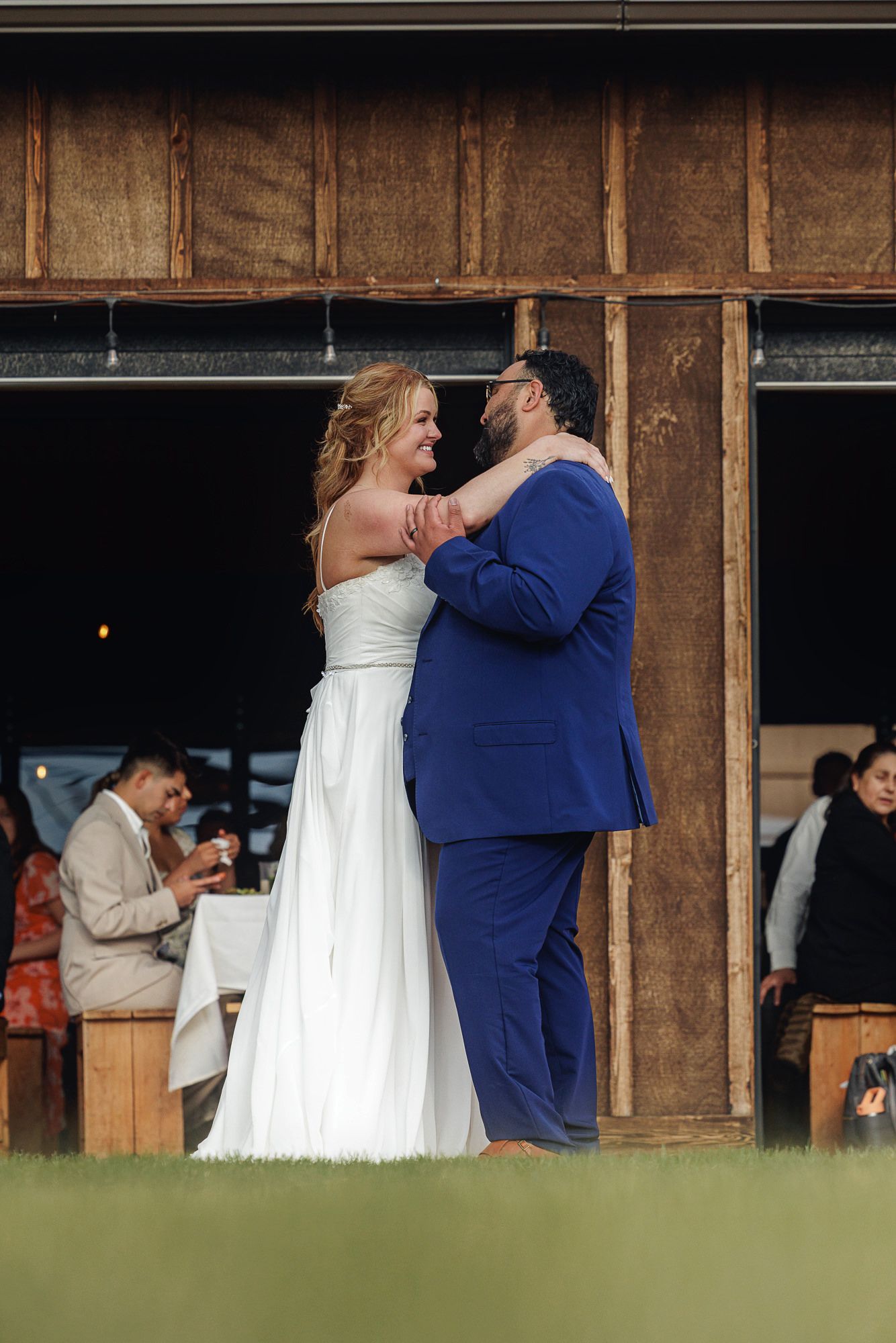 Bride and groom share their first dance outdoors at a rustic barn wedding venue.