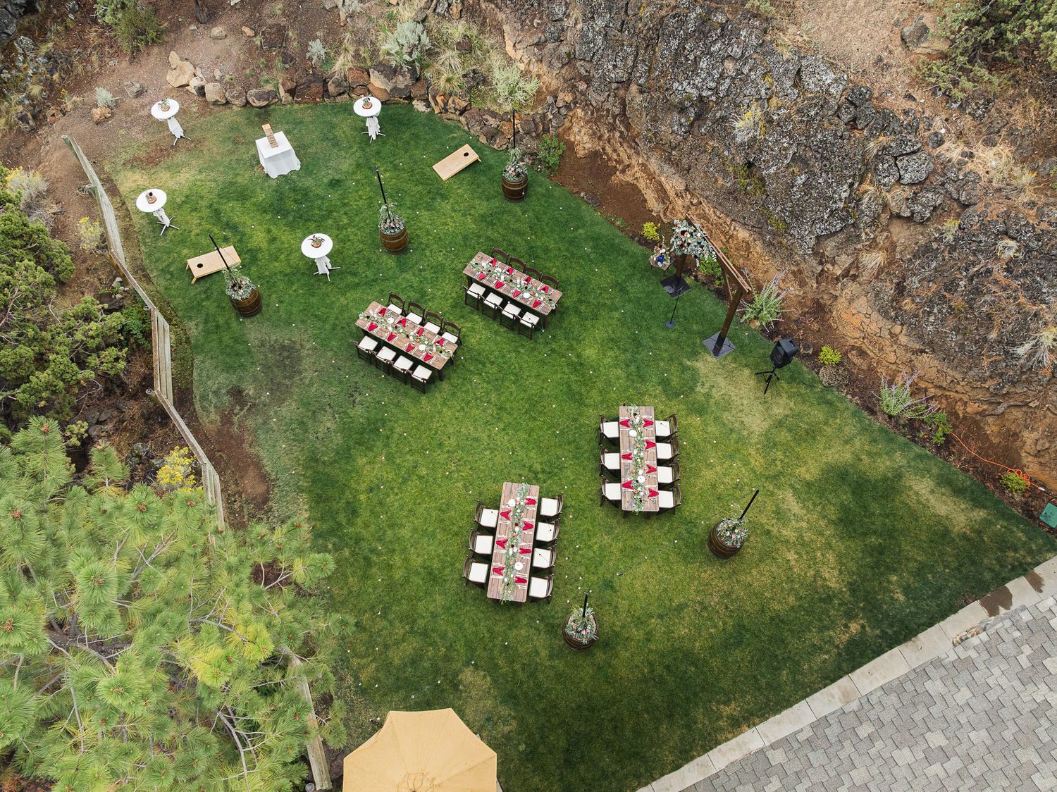 Aerial view of a backyard wedding setup with white chairs arranged in rows on a green lawn.