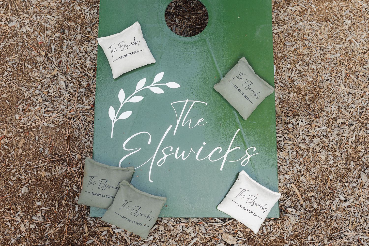 Wedding invitation suite with elegant calligraphy and white leaf design on sage green background with scattered notes.